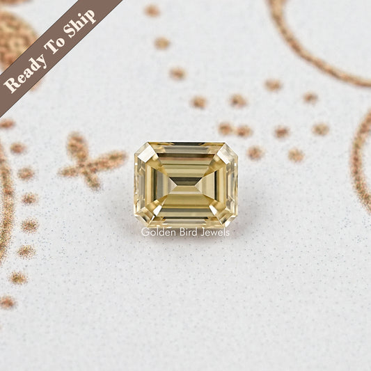 Yellow emerald-cut moissanite gemstone in a rectangular frame, front view, centered.
