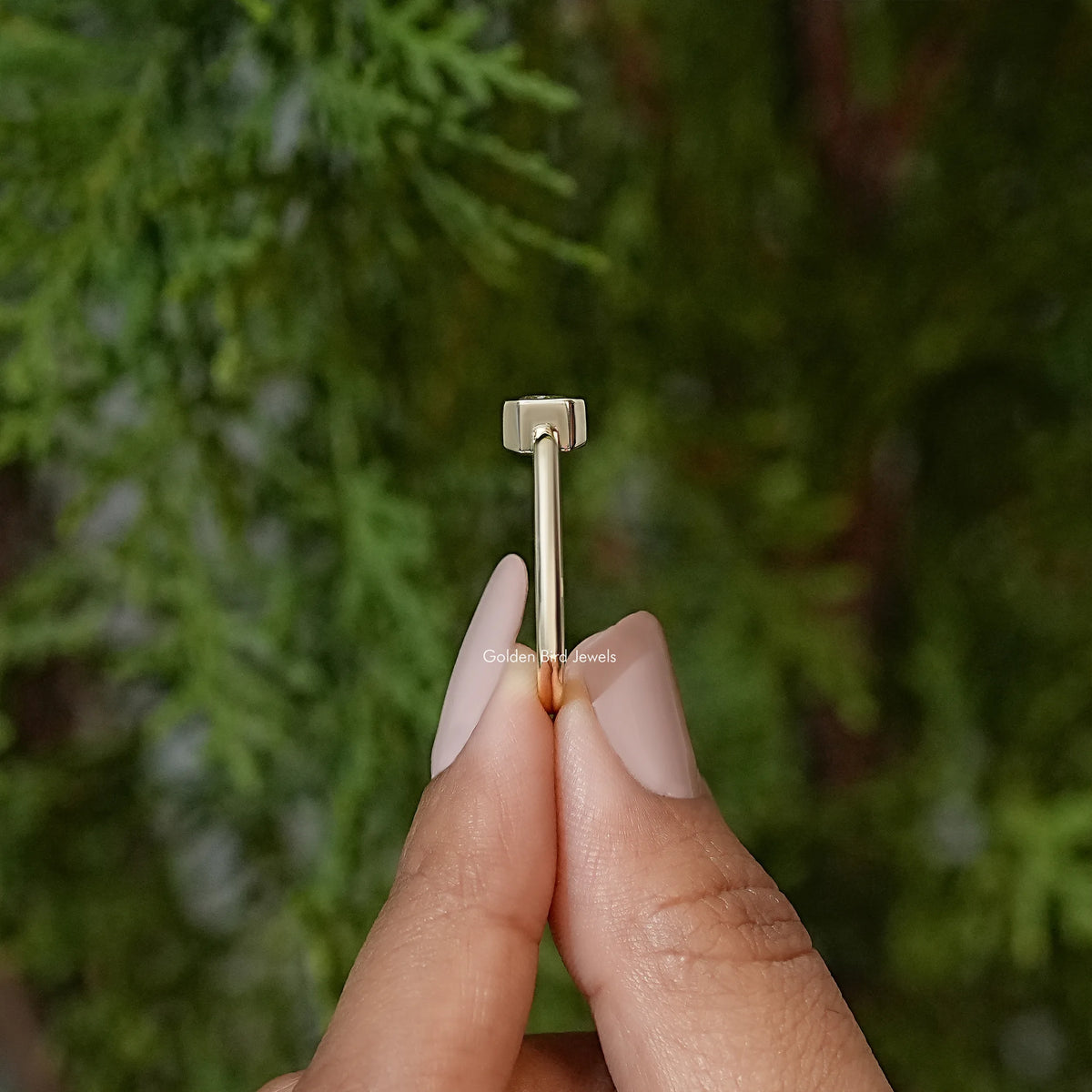 Gold-tone moissanite solitaire ring viewed from the side, bezel setting