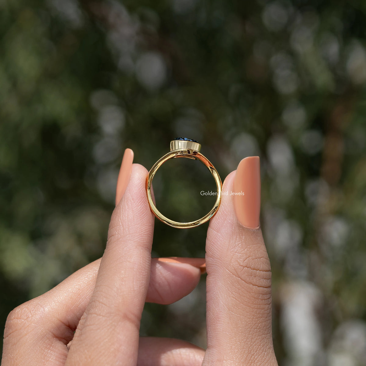 Curved solitaire ring with blue gemstone and gold-toned curved band