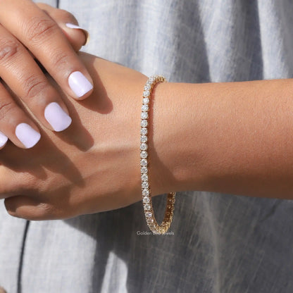 Moissanite tennis bracelet with round-cut stones, gold-tone, on wrist with nails