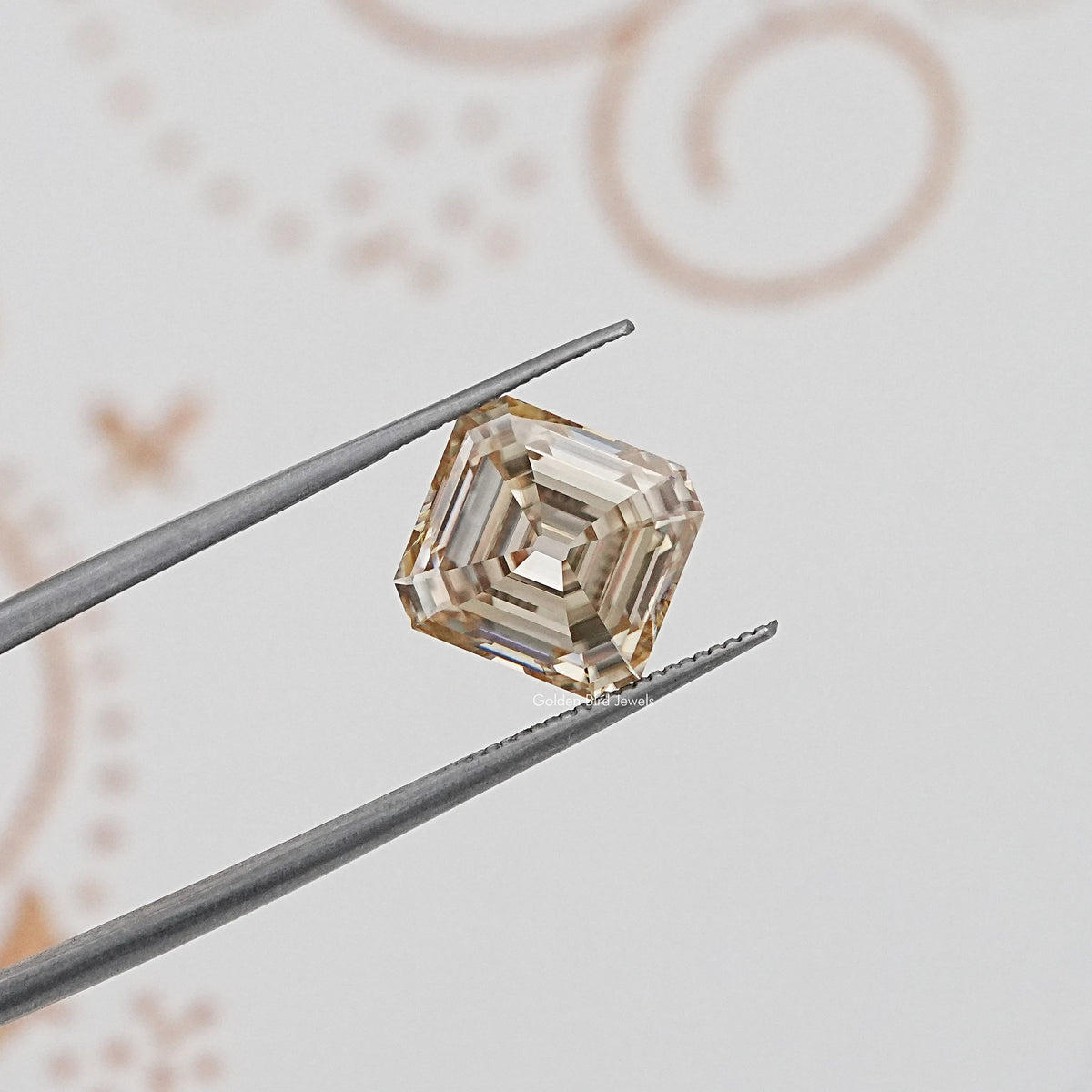 Loose yellow moissanite gemstone, Old Mine Asscher cut held in tweezers