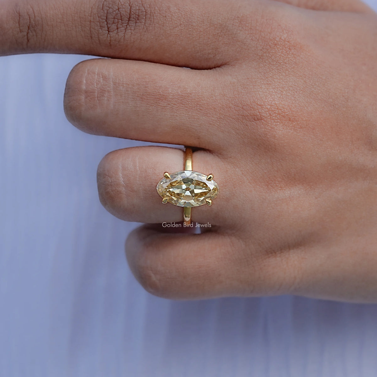 Oval moissanite solitaire ring with gold basket setting, side view on finger