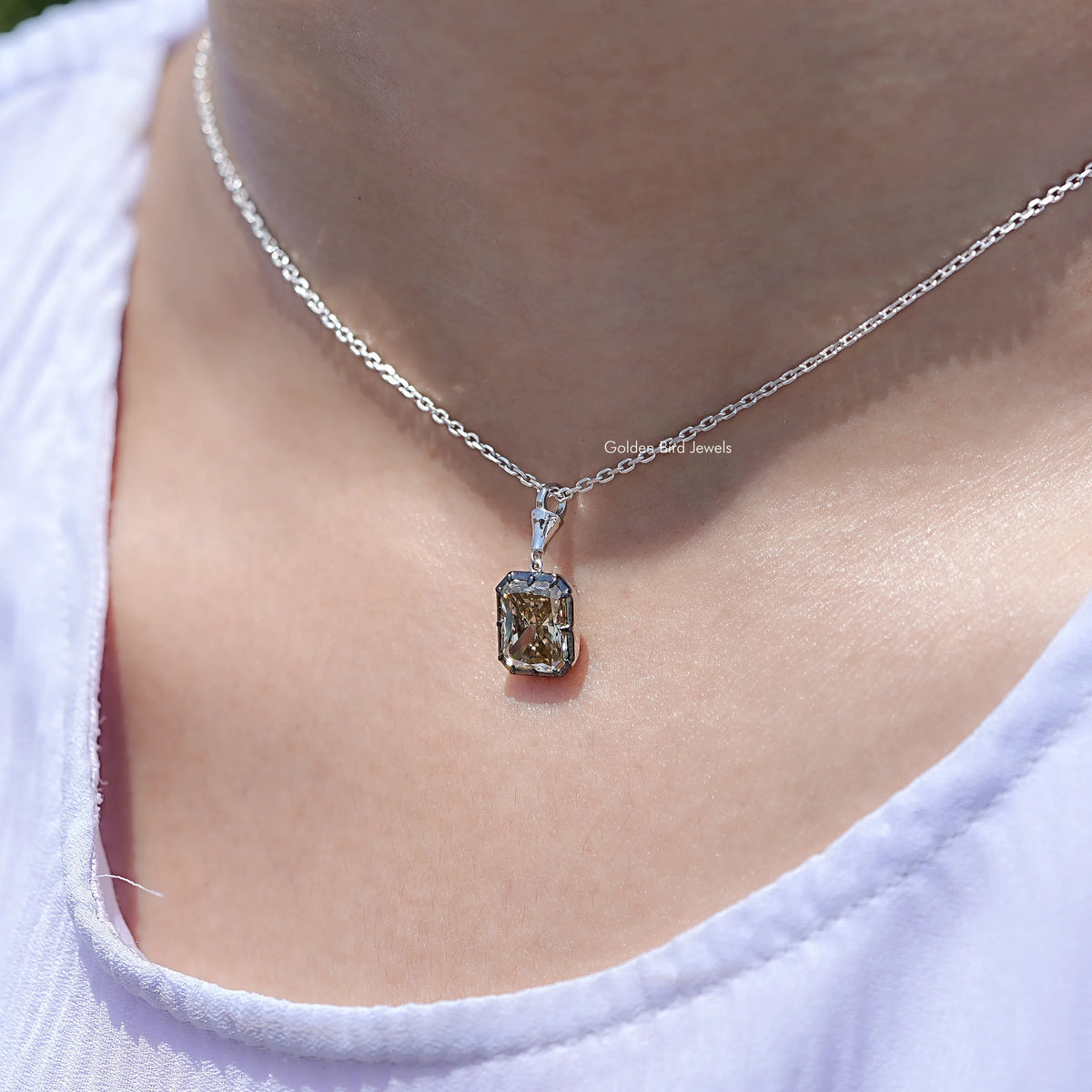 Silver chain moissanite solitaire pendant on neckline of light top