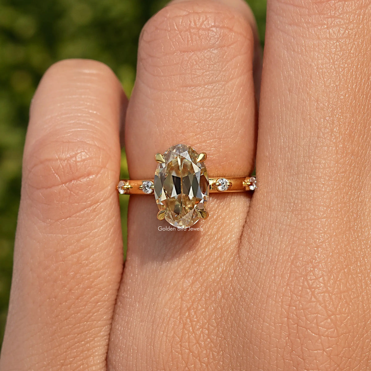 Gold-tone ring with oval center stone, small round side stones, prong setting
