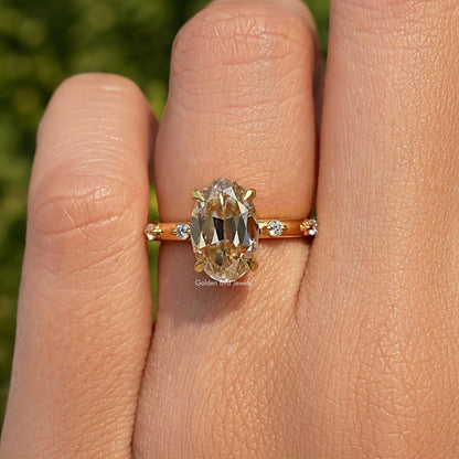 Gold-tone ring with oval center stone, small round side stones, prong setting
