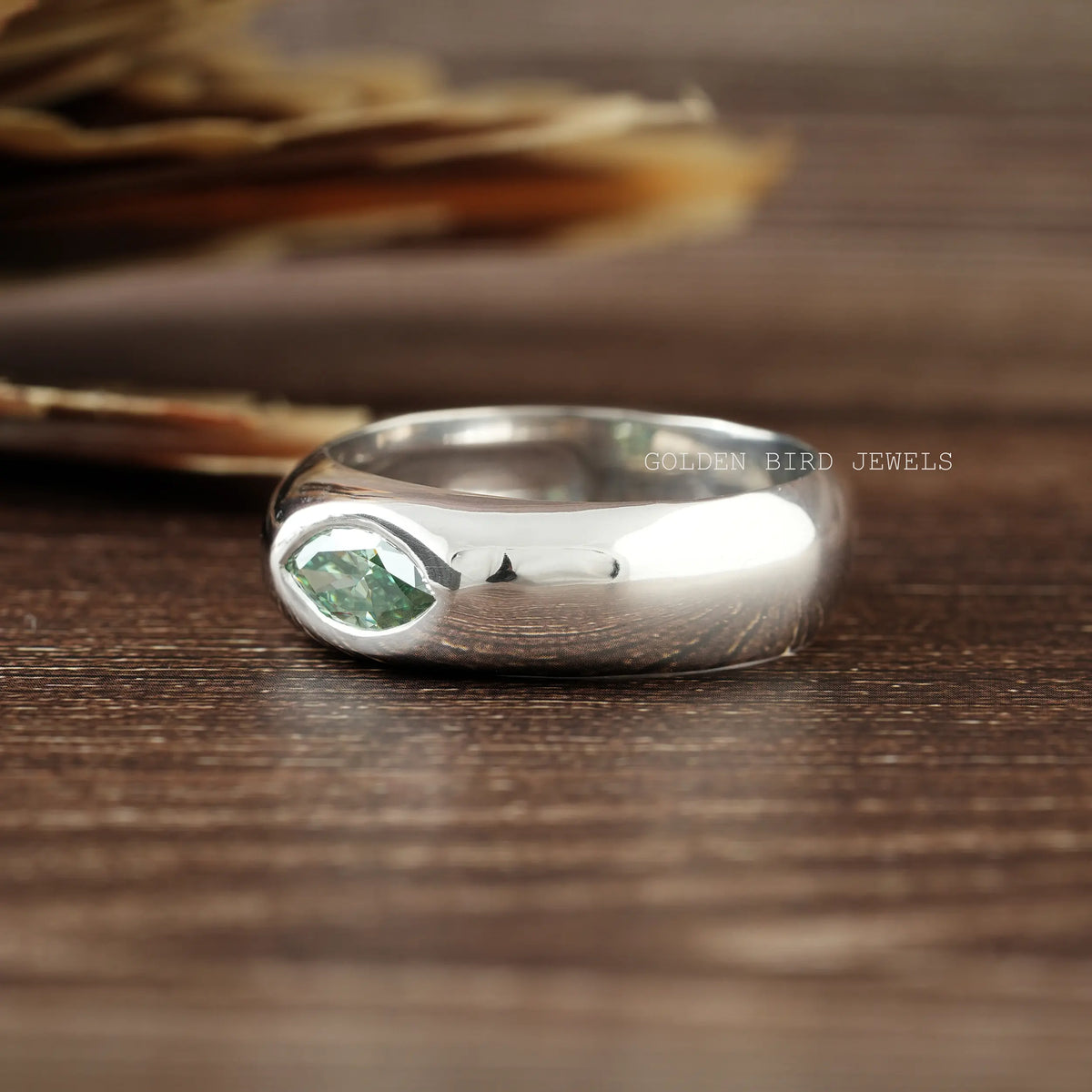 Silver solitaire ring with a green marquise-cut center stone, flush-set.