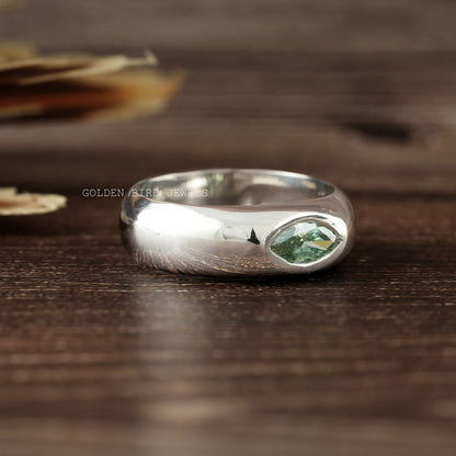 Silver flush-set solitaire ring featuring a green marquise-cut stone on top.