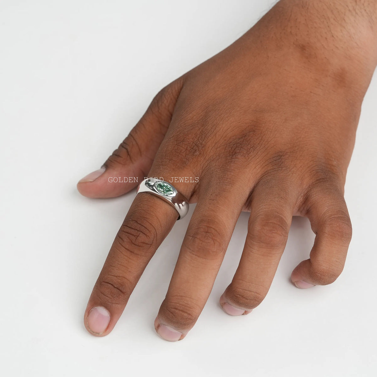 Silver ring with green marquise-cut center stone, worn on fingers.