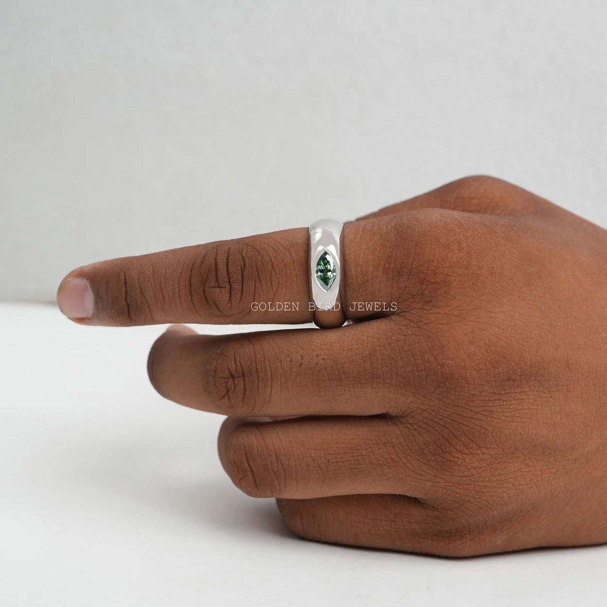 Silver solitaire ring with a green marquise-cut stone, side view on hand.