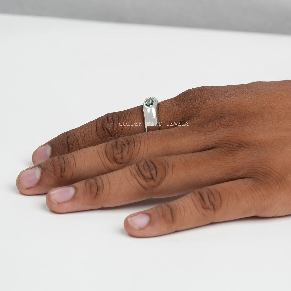 Silver ring with green marquise-cut stone, shown on fingers from above.